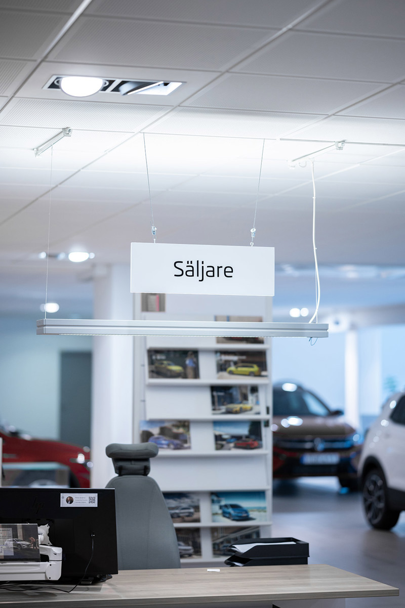 Säljaravdelning i bilhall med säljare-skylt